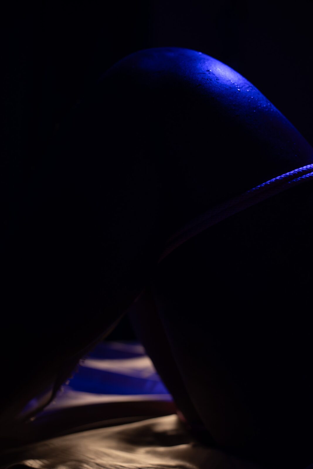 Low-key silhouette: body curve in deep blue light.