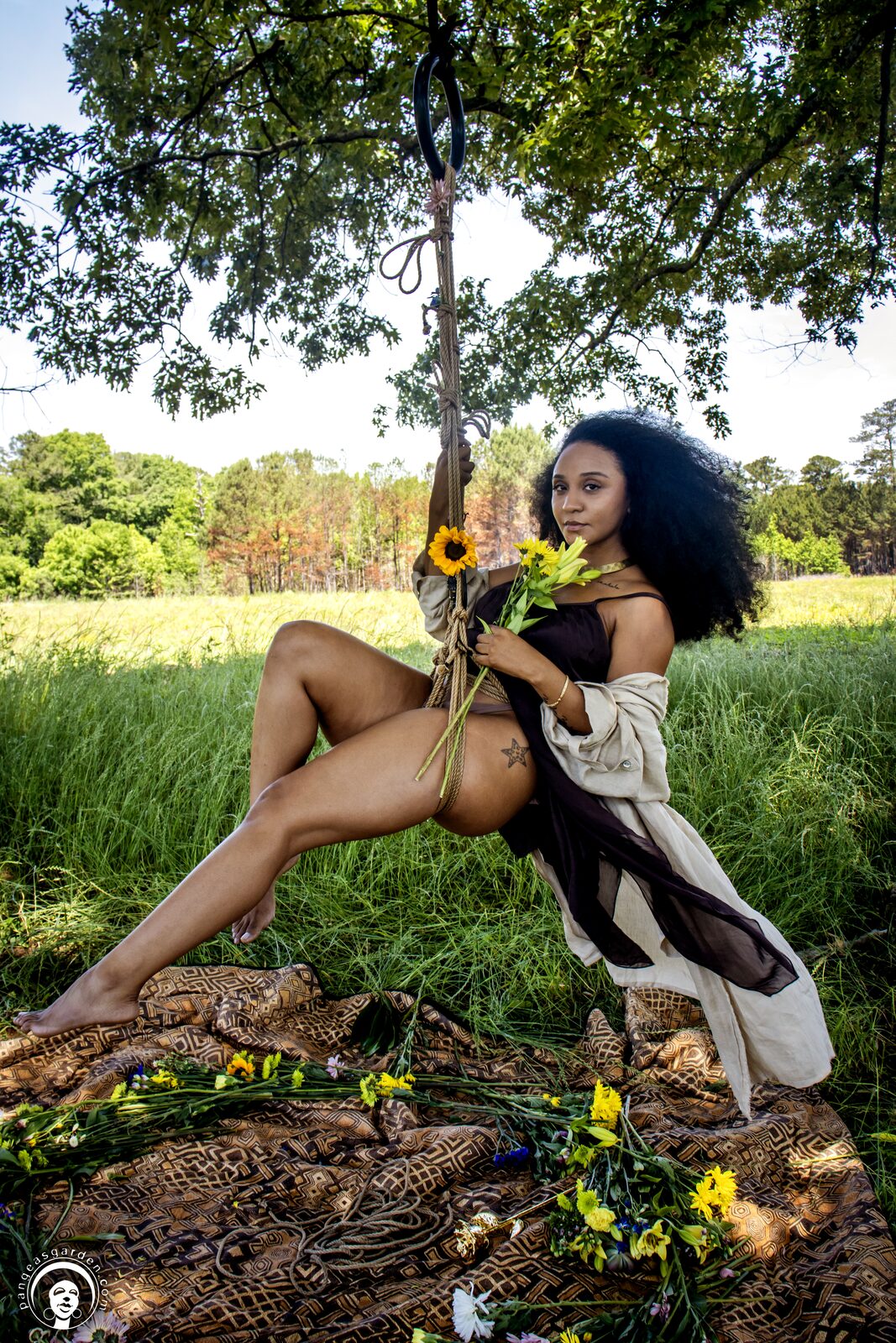 Model holding a woven basket of flowers, jute rope at the hips.
