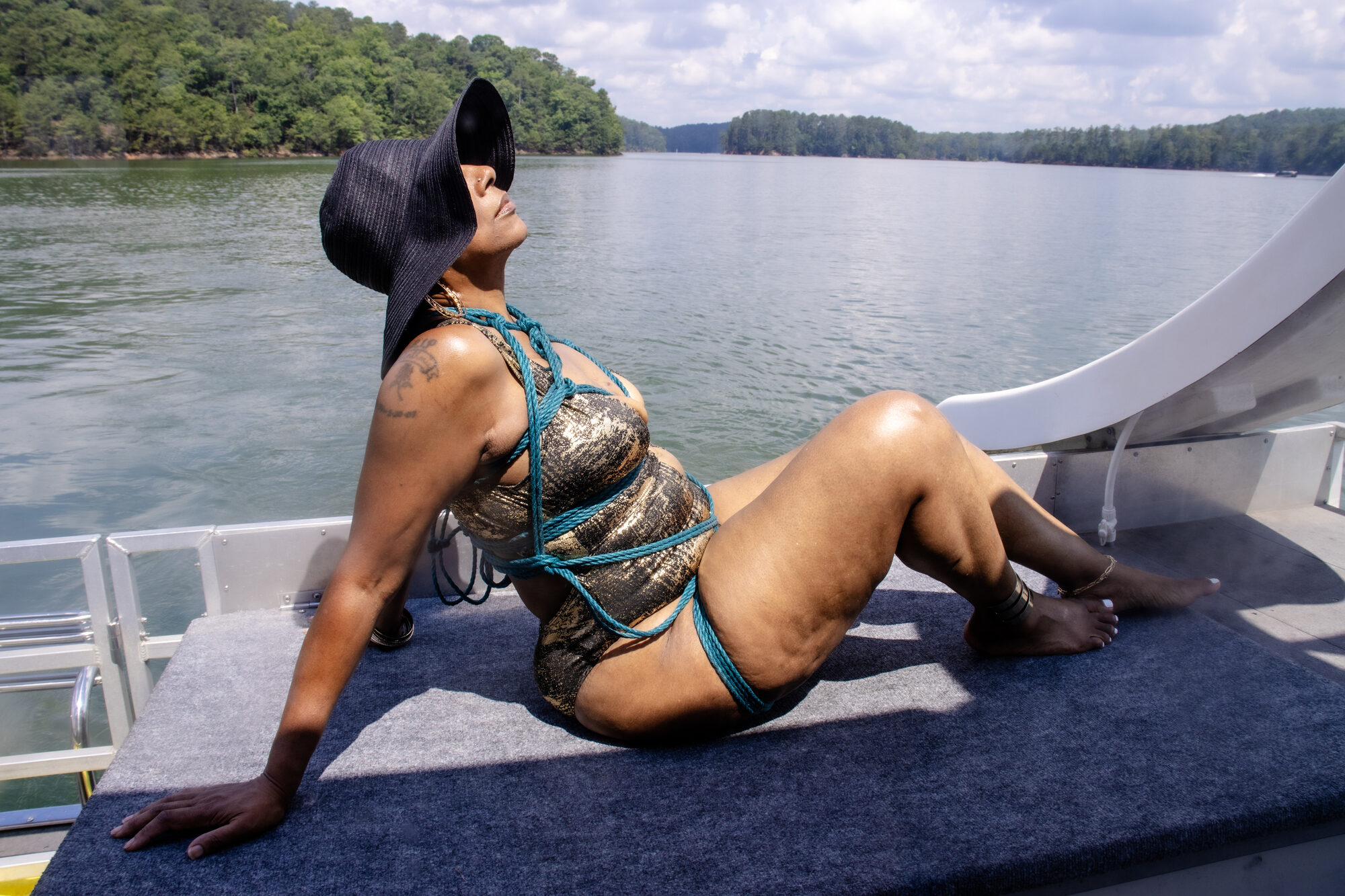 A woman sits at the edge of the boat, looking out over the still water