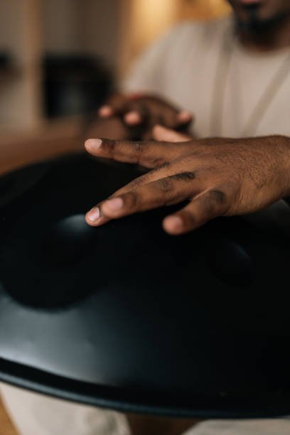 Hands striking drum in rhythmic motion, seen from above